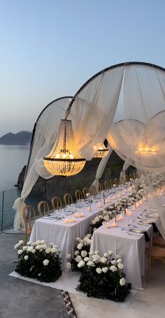 an outdoor dining area with chandeliers and tables set up for a formal function