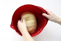 a person holding a ball of bread in a red bowl