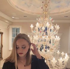 a woman standing in front of a chandelier with her hand on her head