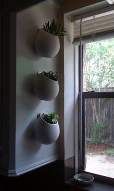 three white planters are on the wall next to a sliding glass door and window