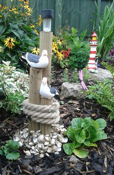 three seagulls are perched on top of a bird feeder in a flower garden