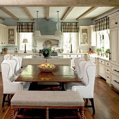 a large kitchen with white cabinets and wooden flooring, along with a dining table surrounded by chairs