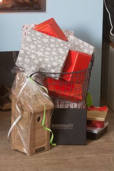 a basket filled with wrapped presents on top of a wooden floor