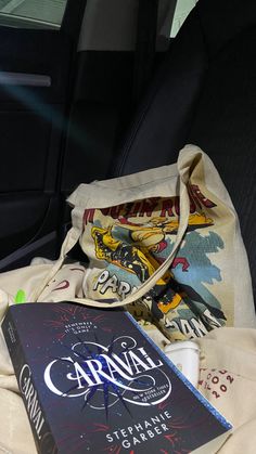 an open book sitting in the back seat of a car next to a bag and cup