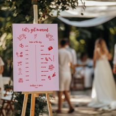 a pink sign that says let's get married on it with people in the background