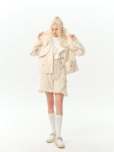 a woman in short shorts and jacket posing for the camera with her hands on her head