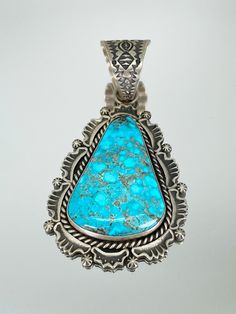 Sterling Silver Pendant made with Kingman Turquoise Overall Size: 1 3/4" by 2 1/2" Bail Size: 3/4" Navajo Silversmith, Harold Joe designs pieces featuring his signature repousse look with bold hand stamped work. Joe is a silversmith based out of New Mexico, often creating traditional southwestern jewelry, using various types of stones. SVHJ110701 Elegant Turquoise Necklace With Large Pendant, Silver Turquoise Necklace With Large Stone, Blue Turquoise Necklace With Large Pendant, Elegant Silver Turquoise Necklace With Large Pendant, Luxury Turquoise Pendant Necklace, Collectible Blue Turquoise Necklace With Large Pendant, Elegant Turquoise Pendant Necklace, Elegant Turquoise Pendant Necklace Collectible, Elegant Sterling Silver Turquoise Pendant Necklace