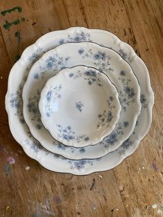 four blue and white plates sitting on top of a wooden table with paint splatters all over them