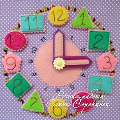 a clock made out of felt with numbers and flowers in the middle on a purple background