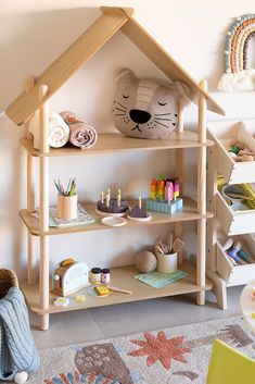 a wooden doll house shelf with craft supplies on it and a stuffed animal in the corner