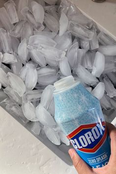 a hand is holding an unopened soft drink in front of ice cubes