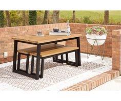 an outdoor table with two benches next to it on a brick wall and tiled patio