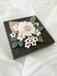 a wooden tray with flowers and leaves on it's side sitting on a bed