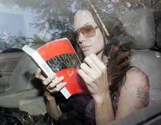 a woman reading a book in the back seat of a car