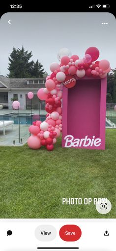 a pink box with balloons on it in the grass next to a building and pool