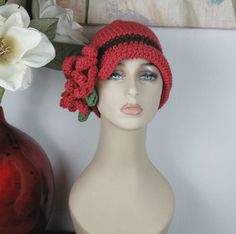 a mannequin head wearing a red crocheted hat with flowers on it