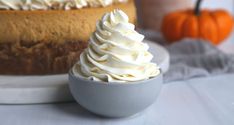 a cake sitting on top of a white plate next to a cup filled with whipped cream