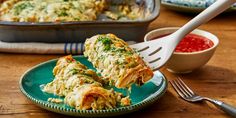 a green plate topped with lasagna covered in cheese next to a bowl of sauce