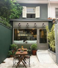 the outside of a restaurant with tables and chairs in front of an open doored window