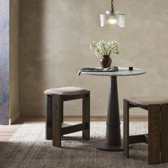 a small table and two stools in a room with a rug on the floor