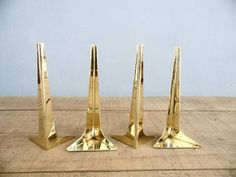 three gold metal candlesticks on a wooden table