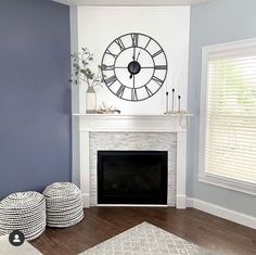 a living room filled with furniture and a clock on the wall above a fire place