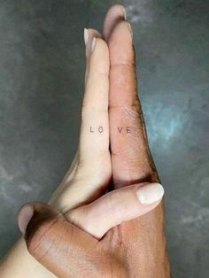 two hands holding each other with the word love tattooed on their fingers