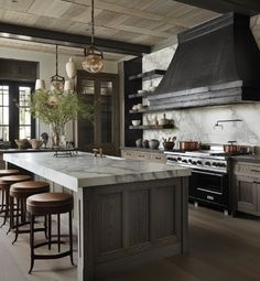 a kitchen with marble counter tops and stools in front of an island that has several pots on it