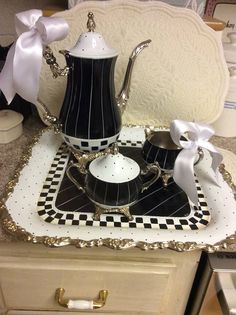 a black and white tea set sitting on top of a table next to a drawer