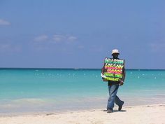 a man walking on the beach carrying a blanket