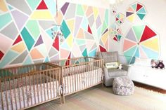 a baby's room decorated in pastel colors with geometric wallpaper and crib