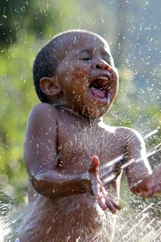 a little boy that is standing in the water with his mouth open and hands out