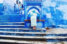 a woman standing on some steps in front of a blue building