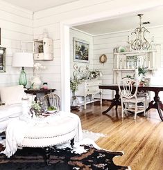 a living room filled with white furniture and decor on top of a hard wood floor