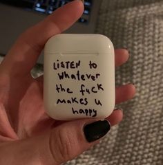 a hand holding an airpods with writing on it that says, listen to whatever the f k makes u happy