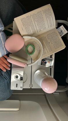 a person sitting on an airplane reading a book and holding a pink object in their hand