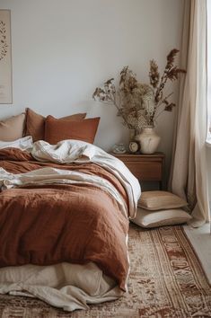 an unmade bed sitting next to a window with lots of pillows on top of it