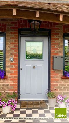 a grey front door with two windows and potted flowers