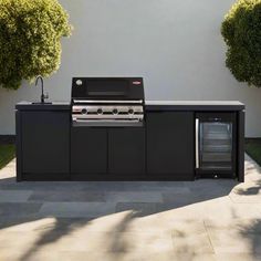 an outdoor kitchen with grill, sink and refrigerator in the middle of a patio area