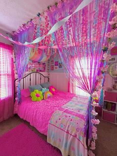 a bedroom decorated in pink, purple and blue with flowers on the canopy over the bed