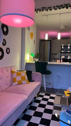 a living room with a checkered floor and pink couch in front of a kitchen