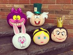 several pumpkins with faces painted on them are lined up in front of a brick wall