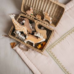 an open suitcase filled with toy animals on top of a bed