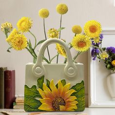 a white purse with yellow flowers in it sitting on a table next to some books