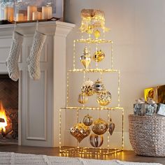 a christmas tree with lights and ornaments in front of a fireplace