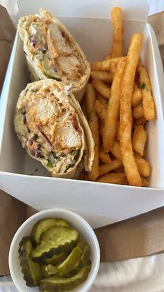 a sandwich and some french fries in a white box on a table with napkins