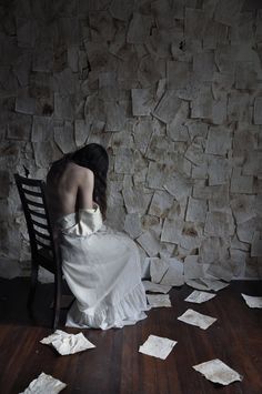 a woman sitting on a chair in front of a wall covered with sheets of paper