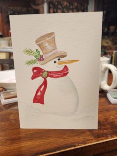 a card with a snowman wearing a hat and scarf on it's head