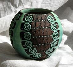 a green and brown vase sitting on top of a white sheet