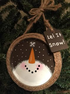 a snowman ornament hanging from a tree with a sign saying let it snow